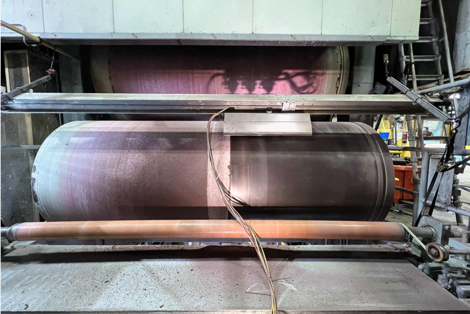 Paper mill dryer can with heavy buildup above the doctor blade and a clean polished surface below after Radiant on-machine cleaning